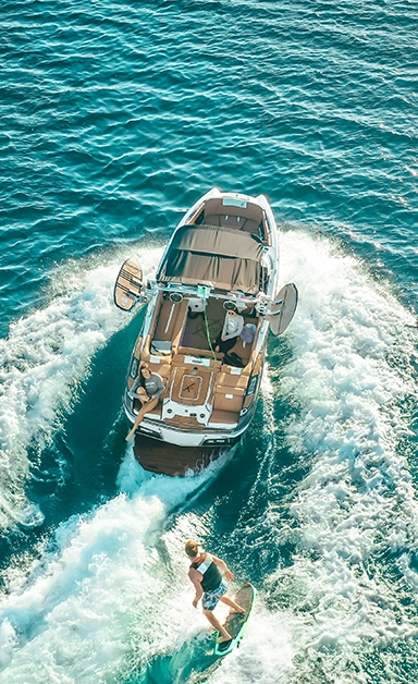 Women on a boat and a man wakeboarding