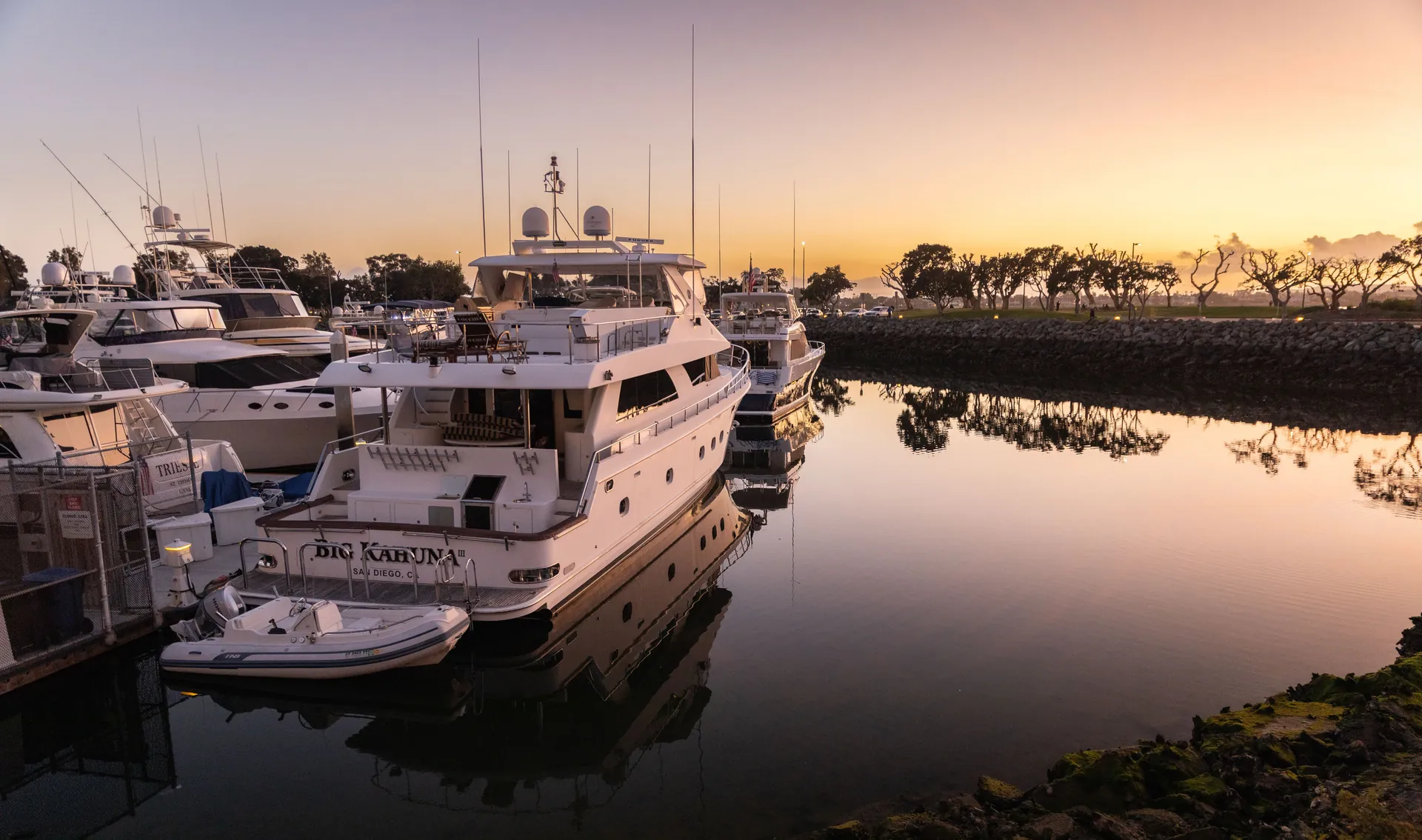 Yachts docked at a serene marina during sunset